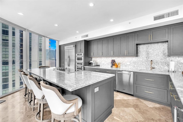 kitchen featuring a breakfast bar, sink, light stone counters, a kitchen island, and stainless steel appliances