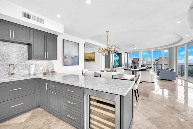 kitchen featuring pendant lighting, sink, gray cabinetry, wine cooler, and kitchen peninsula