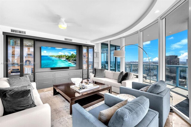 living room featuring ceiling fan and a wall of windows