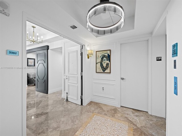 hallway featuring a tray ceiling and a notable chandelier