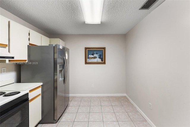 kitchen with a textured ceiling, white cabinetry, stainless steel fridge, range with electric cooktop, and light tile patterned floors