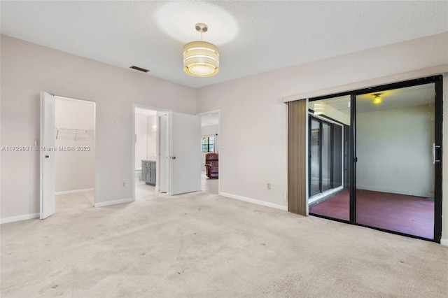 unfurnished bedroom featuring a spacious closet, a textured ceiling, a closet, access to outside, and light colored carpet