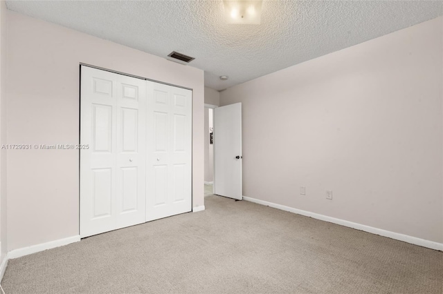 unfurnished bedroom featuring a closet, light carpet, and a textured ceiling