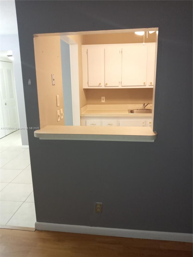 kitchen featuring light tile patterned floors, sink, and white cabinets