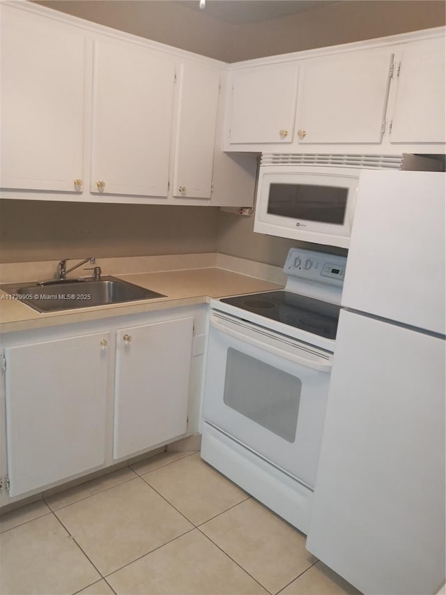 kitchen with white cabinets, white appliances, light tile patterned floors, and sink