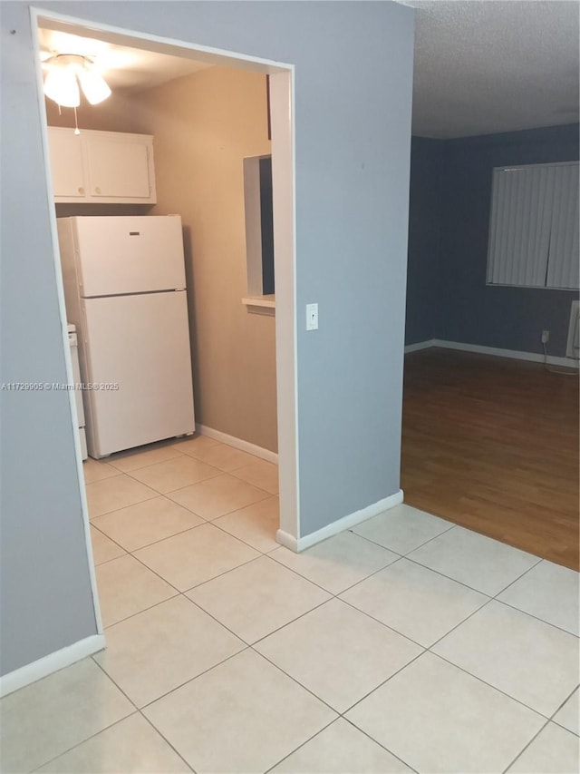 kitchen with white cabinetry, light tile patterned floors, and white fridge