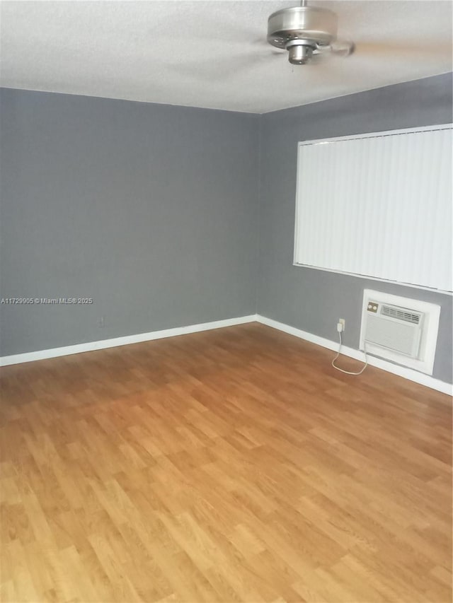 spare room featuring hardwood / wood-style flooring and a wall unit AC