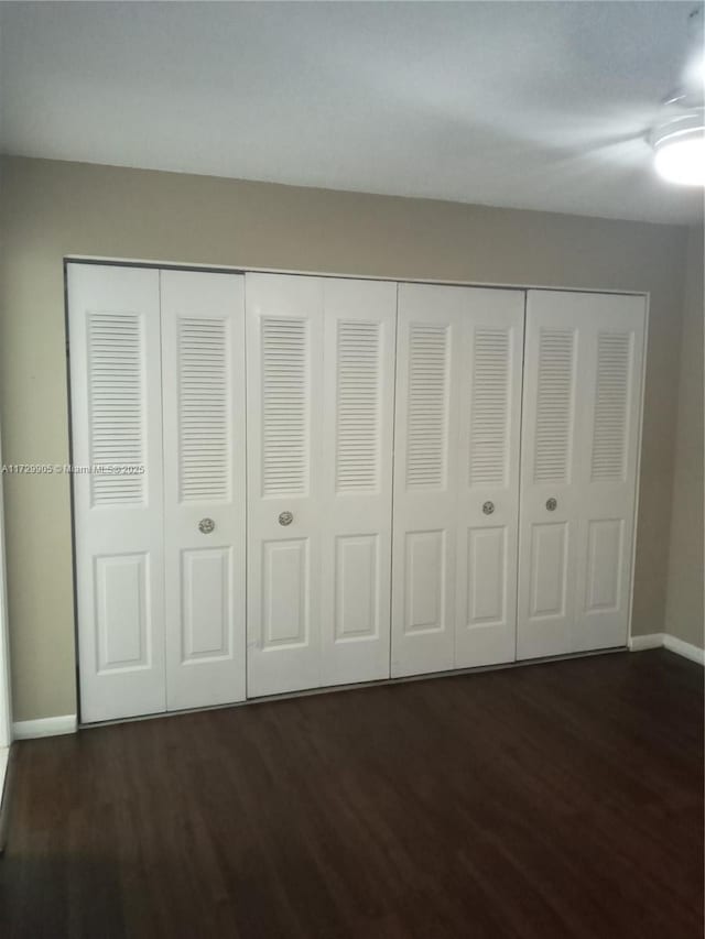 unfurnished bedroom with a closet and dark hardwood / wood-style flooring