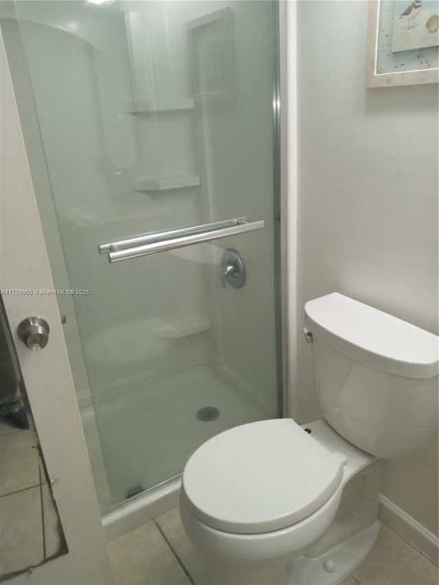 bathroom featuring toilet, tile patterned flooring, and an enclosed shower