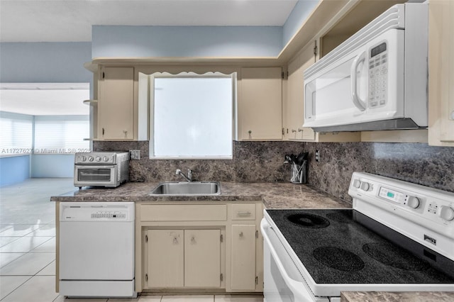 kitchen with sink, white appliances, light tile patterned floors, and cream cabinets