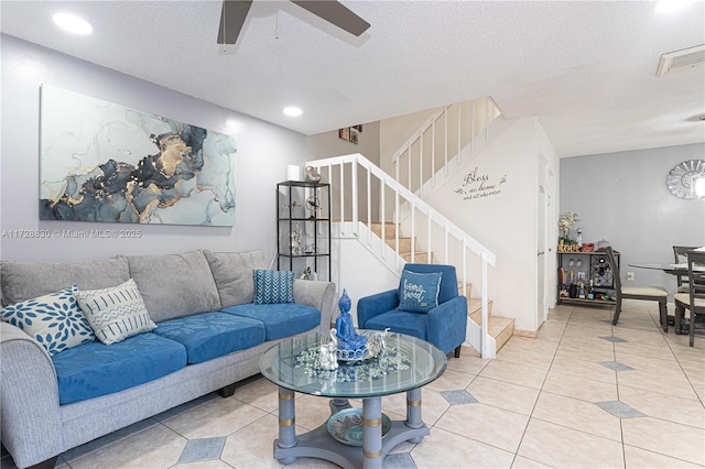 living room featuring ceiling fan, a textured ceiling, and tile patterned flooring