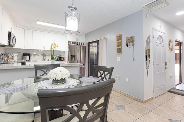 tiled dining space with sink and a textured ceiling