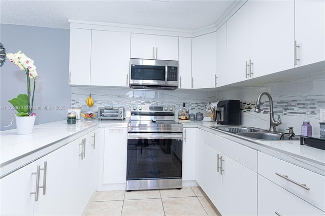 kitchen with white cabinets, stainless steel appliances, decorative backsplash, and sink