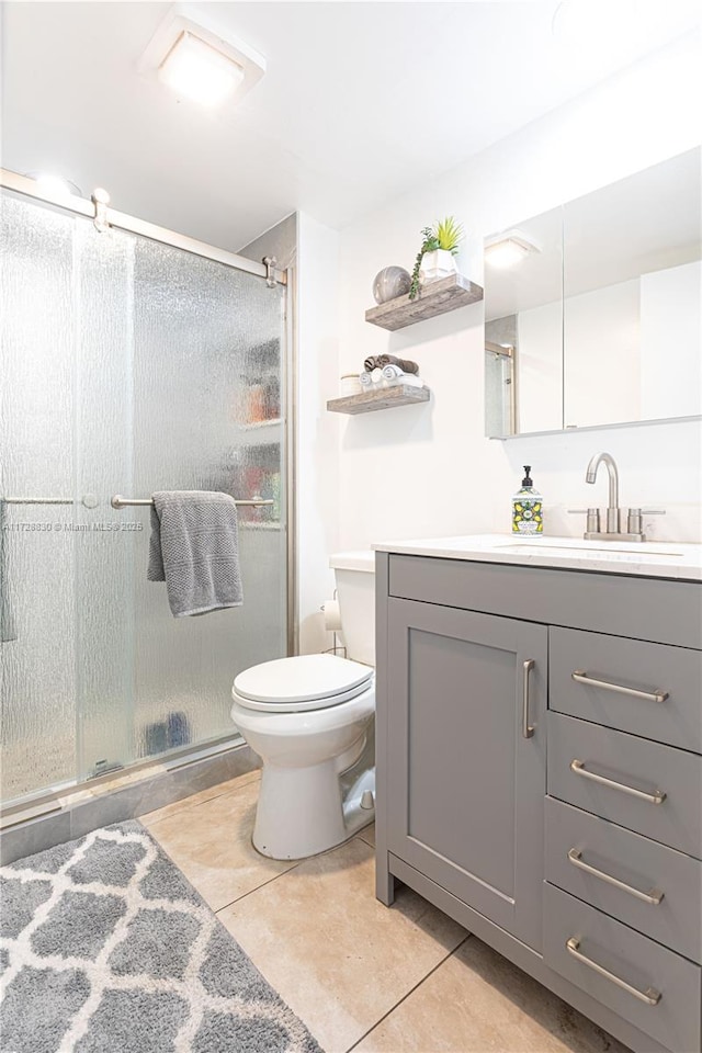 bathroom with tile patterned floors, walk in shower, toilet, and vanity