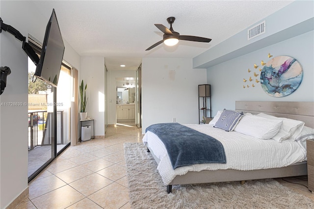 bedroom featuring ceiling fan, ensuite bathroom, a textured ceiling, and light tile patterned flooring