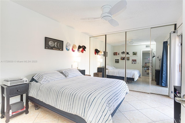 bedroom with a closet, ceiling fan, light tile patterned floors, and a textured ceiling