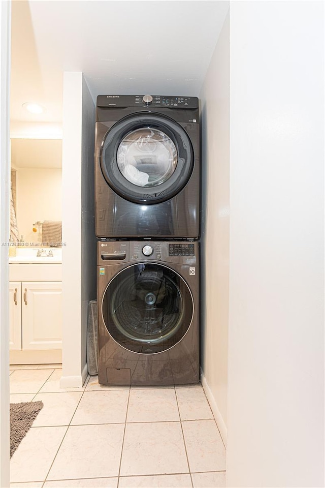 laundry area with light tile patterned floors and stacked washer / dryer