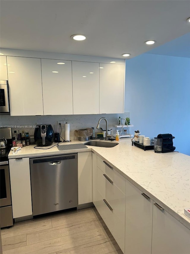 kitchen featuring light hardwood / wood-style floors, white cabinetry, sink, stainless steel appliances, and light stone counters