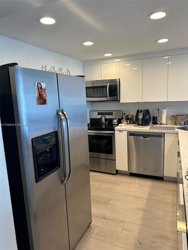 kitchen with white cabinets, stainless steel appliances, and light hardwood / wood-style floors