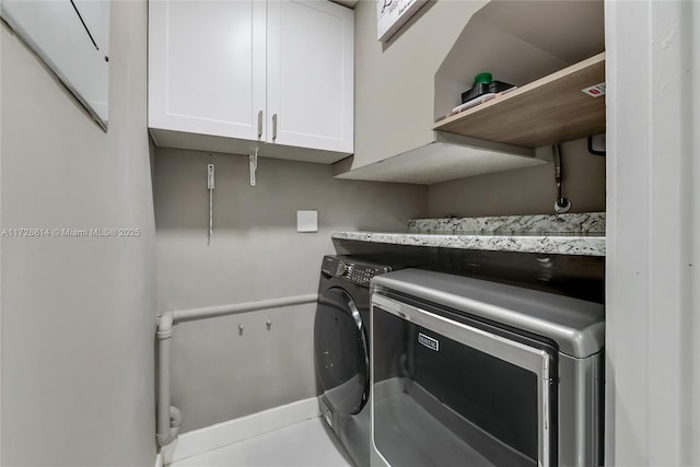 laundry room with independent washer and dryer, cabinets, and light tile patterned flooring