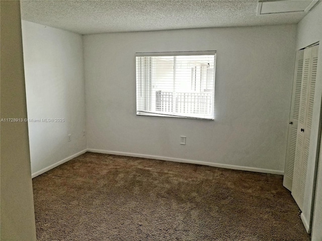 unfurnished bedroom with dark colored carpet, a textured ceiling, and a closet