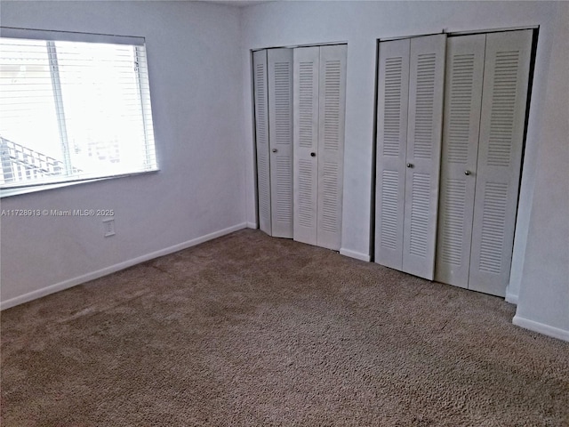 unfurnished bedroom with multiple closets and carpet floors