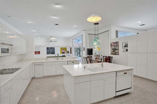 kitchen featuring a wealth of natural light, white appliances, decorative light fixtures, white cabinetry, and a kitchen island with sink