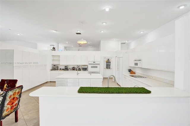 kitchen with pendant lighting, white appliances, white cabinetry, an island with sink, and light tile patterned flooring