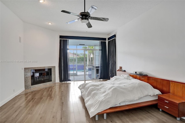 bedroom with access to exterior, ceiling fan, light hardwood / wood-style flooring, and a textured ceiling