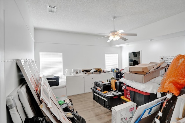 living room featuring ceiling fan, light hardwood / wood-style flooring, and a textured ceiling