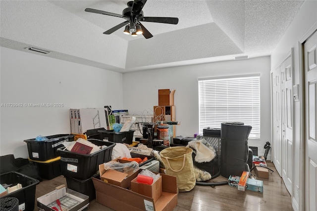 office featuring hardwood / wood-style flooring, a textured ceiling, ceiling fan, and a raised ceiling