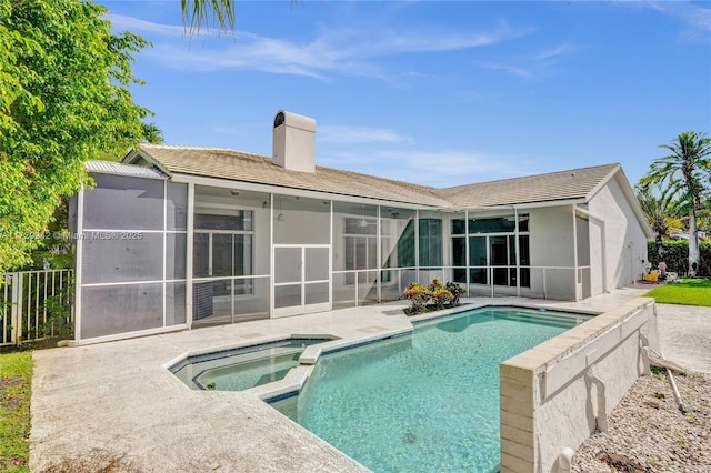 rear view of house featuring a sunroom, a patio, and a swimming pool with hot tub