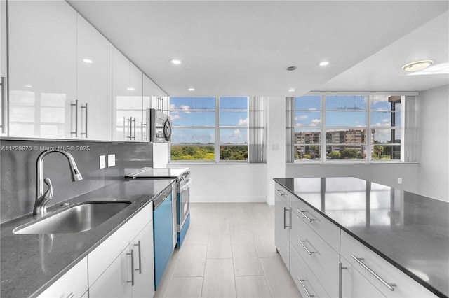 kitchen featuring white cabinetry, decorative backsplash, sink, dark stone countertops, and stainless steel appliances