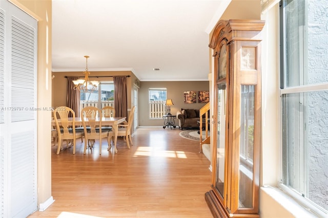 dining room featuring ornamental molding, a notable chandelier, light wood-style flooring, and baseboards