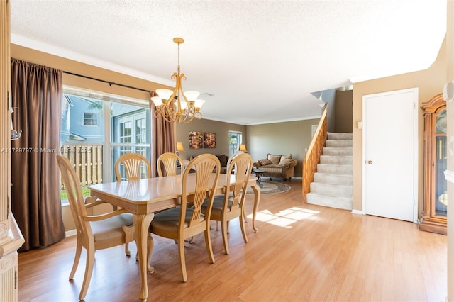 dining area featuring light wood-style flooring, stairway, ornamental molding, a textured ceiling, and a notable chandelier