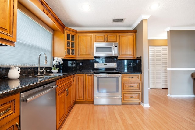 kitchen with stainless steel appliances, light wood-type flooring, a sink, and brown cabinets