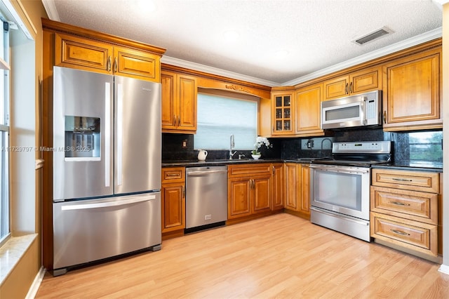 kitchen featuring appliances with stainless steel finishes, brown cabinets, and visible vents