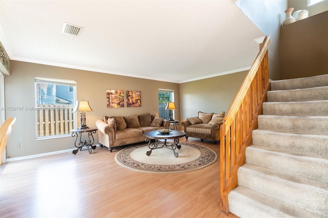 living area with ornamental molding, visible vents, stairway, and wood finished floors