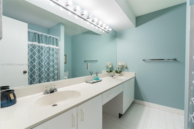 full bath featuring baseboards, a sink, toilet, and double vanity