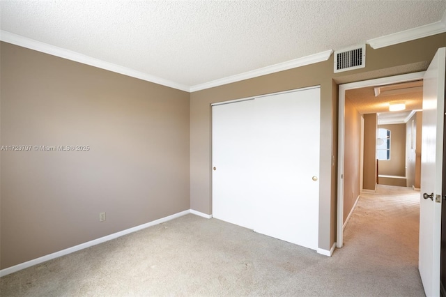 unfurnished bedroom featuring a textured ceiling, light carpet, visible vents, a closet, and crown molding