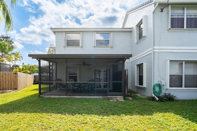 back of house with a lawn, fence, a sunroom, and stucco siding