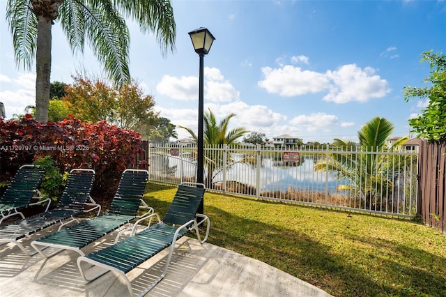 view of patio with a water view and fence