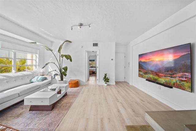 living room with light hardwood / wood-style floors and a textured ceiling