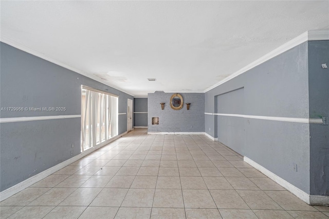 tiled spare room featuring brick wall and crown molding