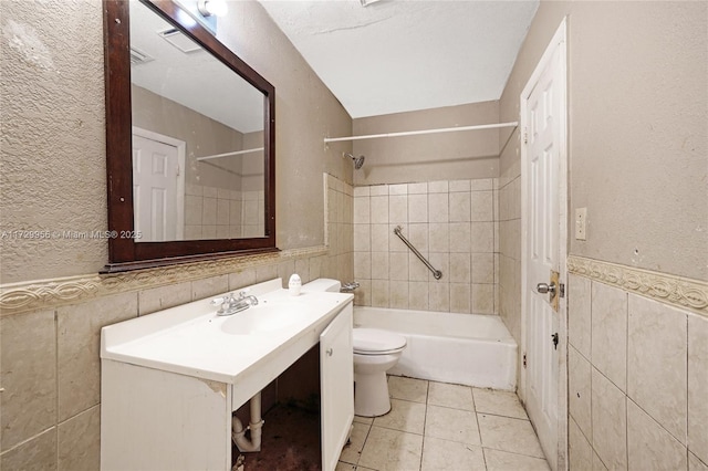 full bathroom featuring tiled shower / bath combo, tile patterned flooring, vanity, tile walls, and toilet