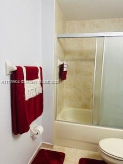 bathroom featuring toilet, shower / bath combination with glass door, and tile patterned flooring