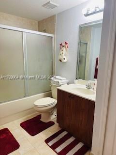 full bathroom featuring toilet, vanity, shower / bath combination with glass door, and tile patterned flooring