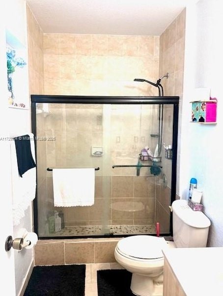 bathroom featuring toilet, an enclosed shower, tile patterned floors, and vanity