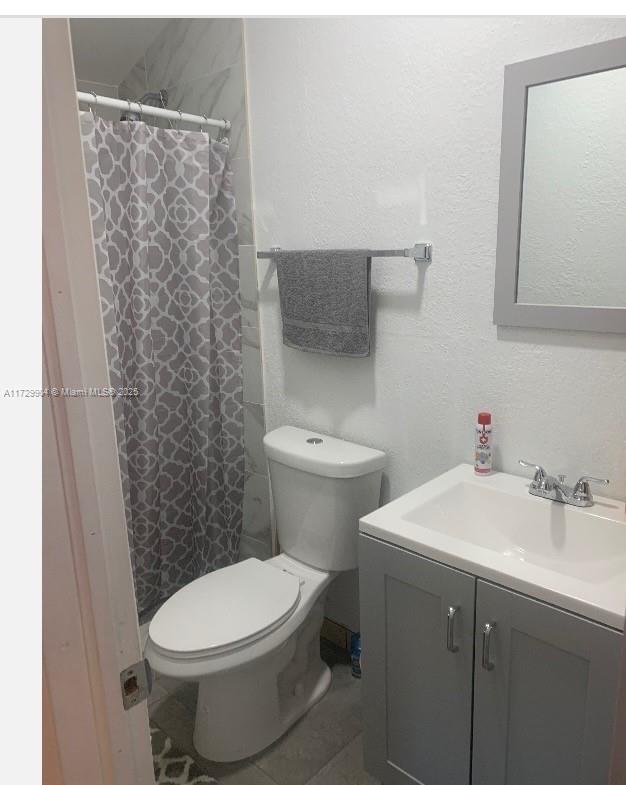 bathroom featuring toilet, a shower with shower curtain, and vanity