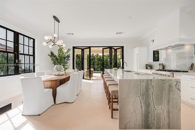 dining room with sink, crown molding, and a chandelier